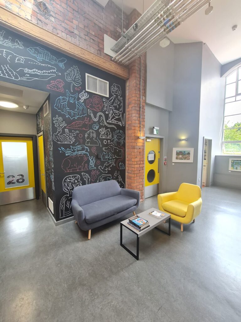 Meeting area with sofa and armchair, decorated graffiti wall in the background